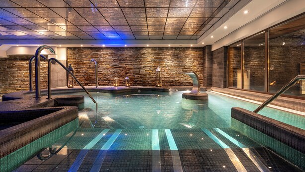 An indoor swimming pool with stone walls and a tiled floor. - Hotel Val De Neu (Naut Aran)
