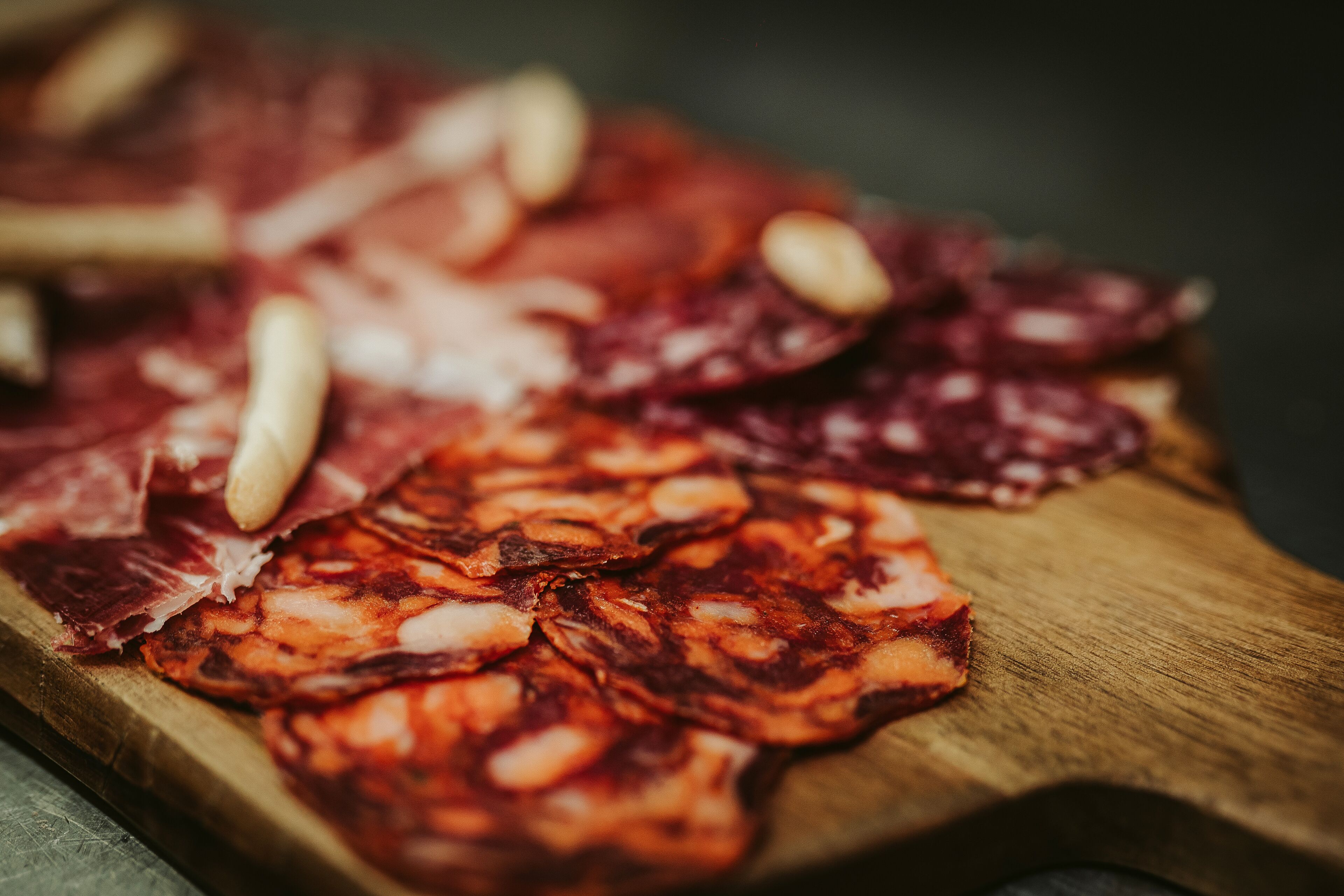 A wooden board with various types of cured meats.