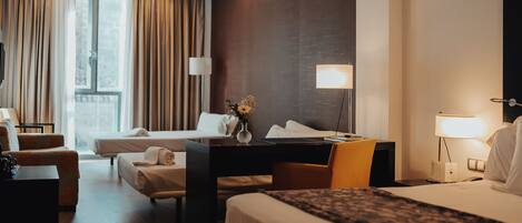 Una habitación de hotel con una cama, dos sofás, un escritorio y una lámpara.