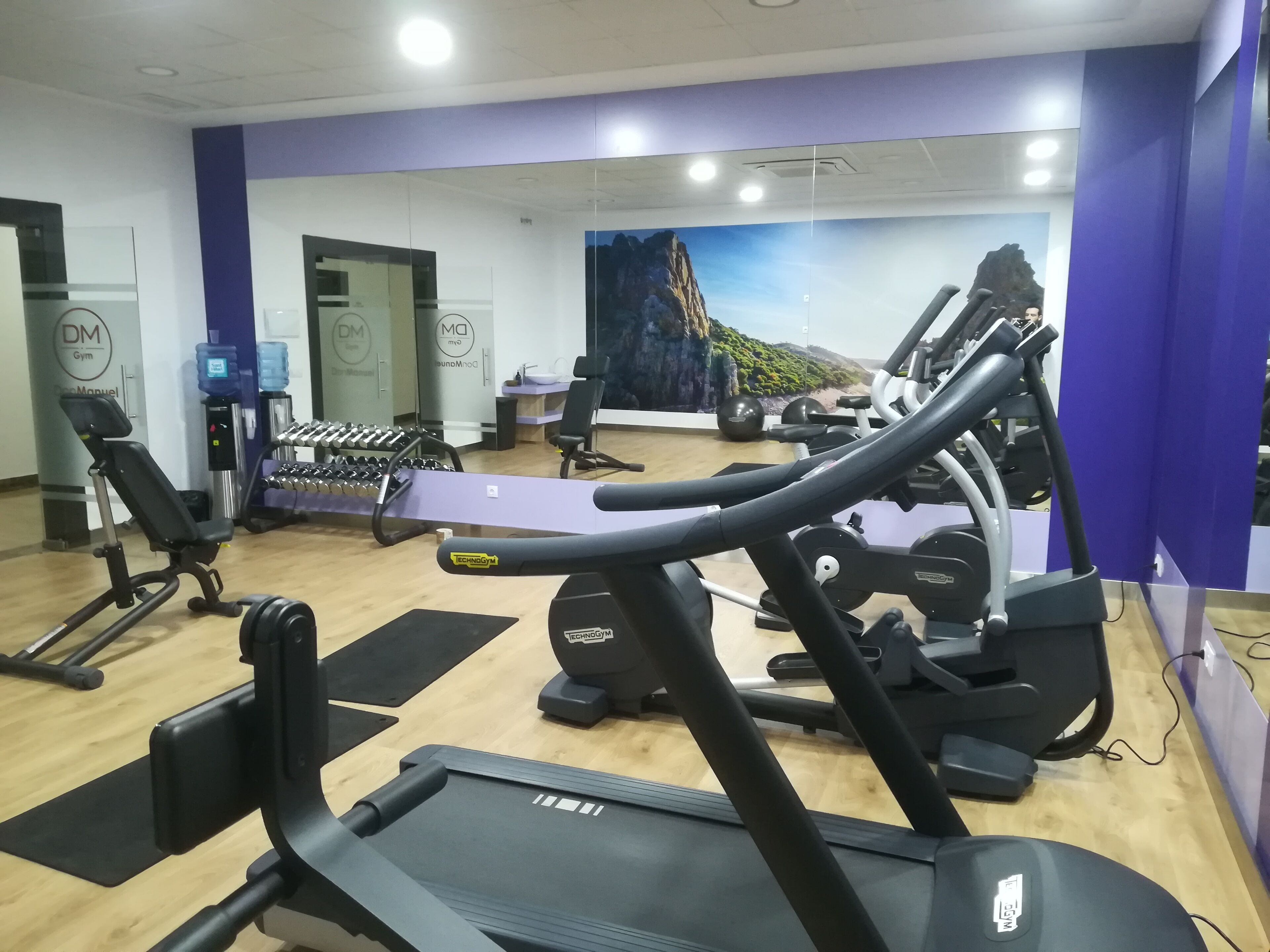 A gym with exercise equipment, including treadmills and dumbbells.