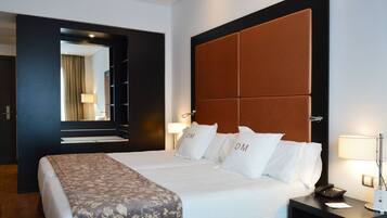 A hotel room with a large bed, a headboard, two bedside lamps, a bedside phone, and a nightstand.