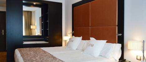 A hotel room with a large bed, a headboard, two bedside lamps, a bedside phone, and a nightstand.