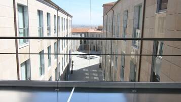 Vista a través de una ventana que muestra una alfombra roja, reflejando edificios con numerosas ventanas y un cielo despejado.