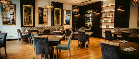 A modern restaurant with wooden flooring, plush seating, and ambient lighting.