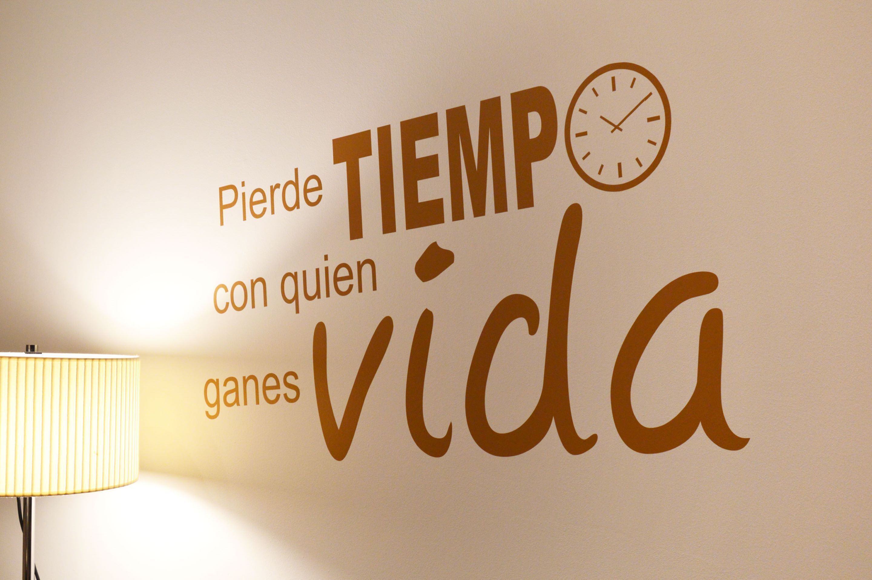 A wall with the text "Pide tiempo con quien ganas de vida" and a clock.