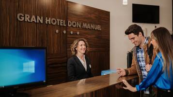 Uma receção de hotel com um painel de parede de madeira exibindo o nome "GRAN HOTEL DON MANUEL".