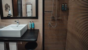 A bathroom with a white sink, mirror, and towel rack. There are two bottles on the counter.