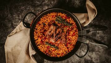 Un plat de riz agrémenté de viande et de légumes, une fourchette et une serviette en tissu, le tout posé sur une surface sombre.