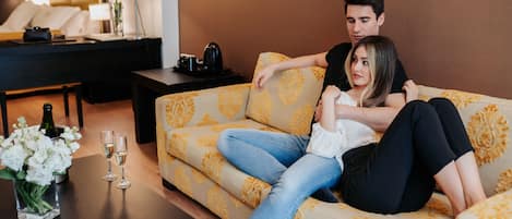 Una pareja sentada en un sofá estampado en un moderno salón con una mesa de centro, una lámpara y un florero.