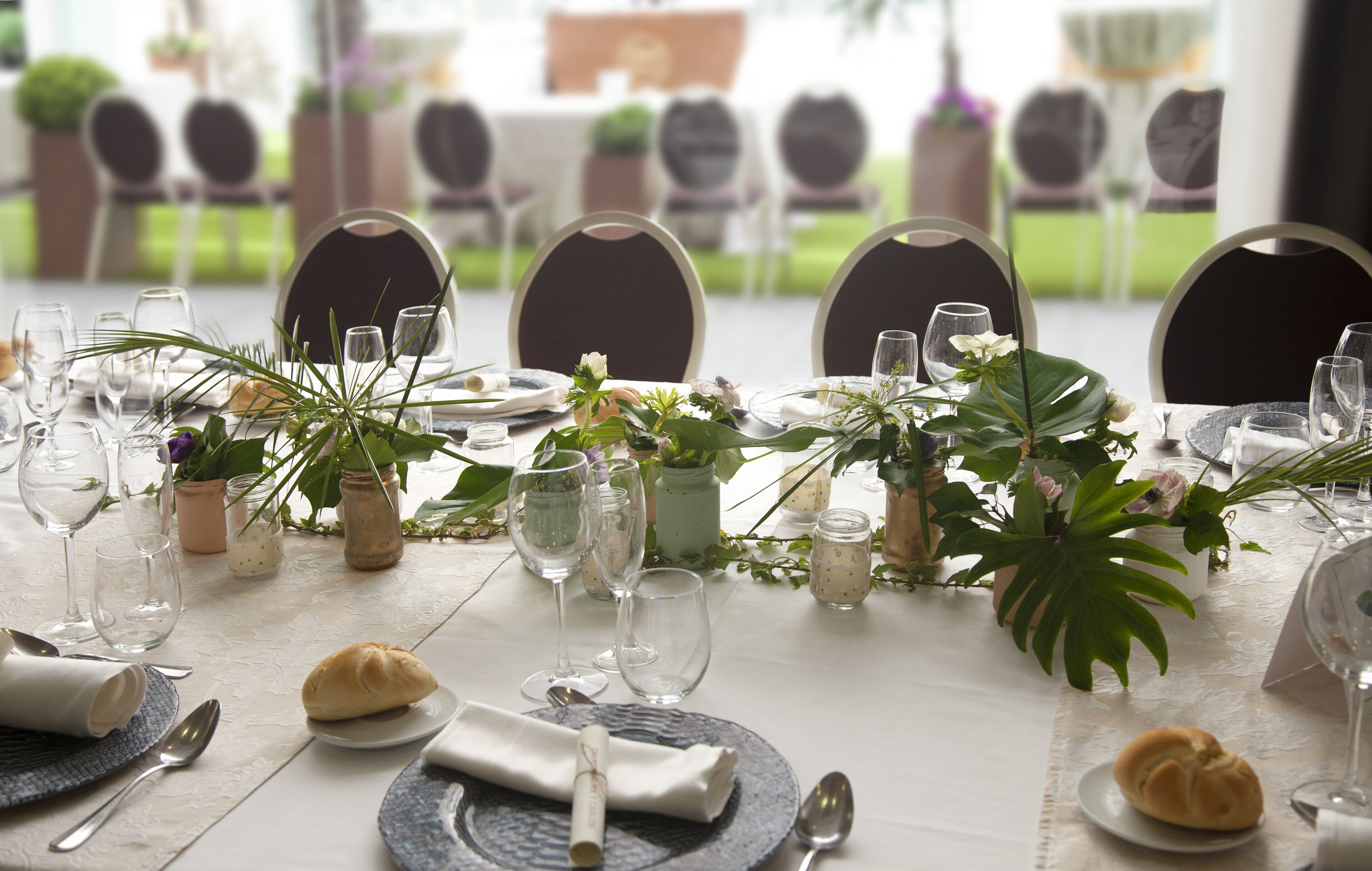 A dining table set with plates, glasses, and cutlery, surrounded by chairs.