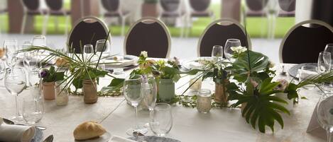 A dining table set with plates, glasses, and cutlery, surrounded by chairs.