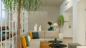 A modern living room with a sectional sofa, glass coffee table, and decorative plants.