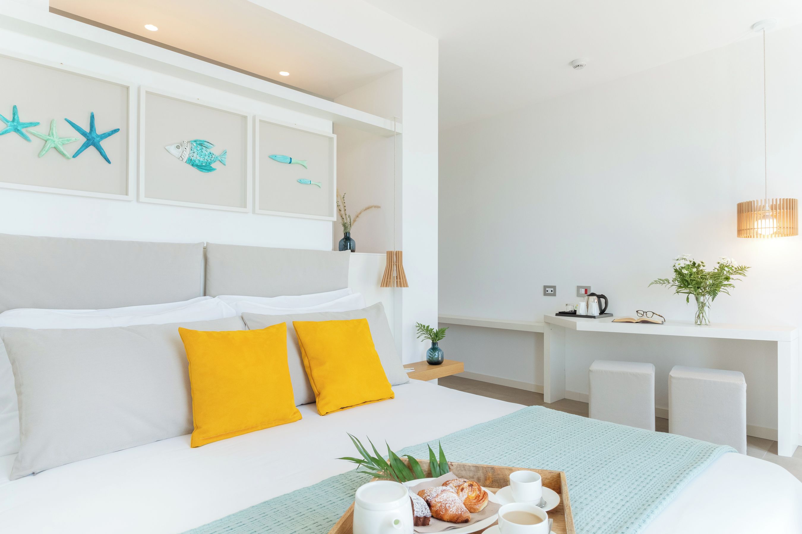 Une chambre d’hôtel moderne équipée d’un lit, d’un plateau de petit-déjeuner et d’un bureau avec une chaise.