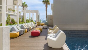 A poolside area with lounge chairs and ottomans arranged along a wooden deck.