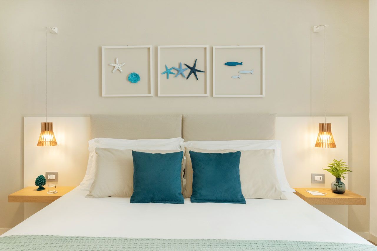 Een keurig opgemaakt slaapkamer met een bed, twee nachtkastjes en wanddecoratie.