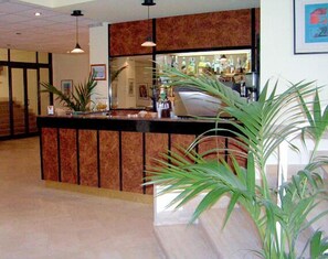 A reception area with a counter, potted plants, and a bar area with bottles. - Albatros Beach Hotel - Letojanni (Letojanni)