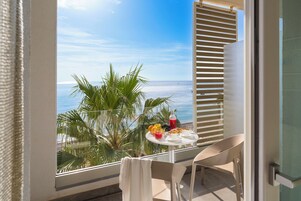 Un balcón con una mesa dispuesta para el desayuno, con vista al océano.