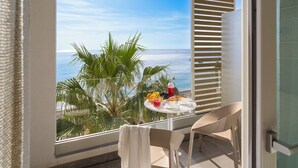 A balcony with a table set for breakfast, overlooking the ocean.