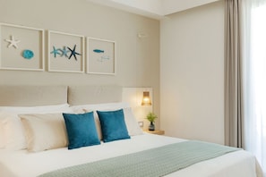 A hotel room with a bed, a nightstand with a lamp, and wall art featuring starfish and fish. - Albatros Beach Hotel - Letojanni (Letojanni)