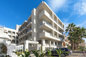 A multi-story hotel with balconies, a parking area, and tropical plants. - Albatros Beach Hotel - Letojanni (Letojanni)
