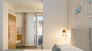 A hotel room with a bed, a nightstand, a lamp, and a view of the outside through a window.