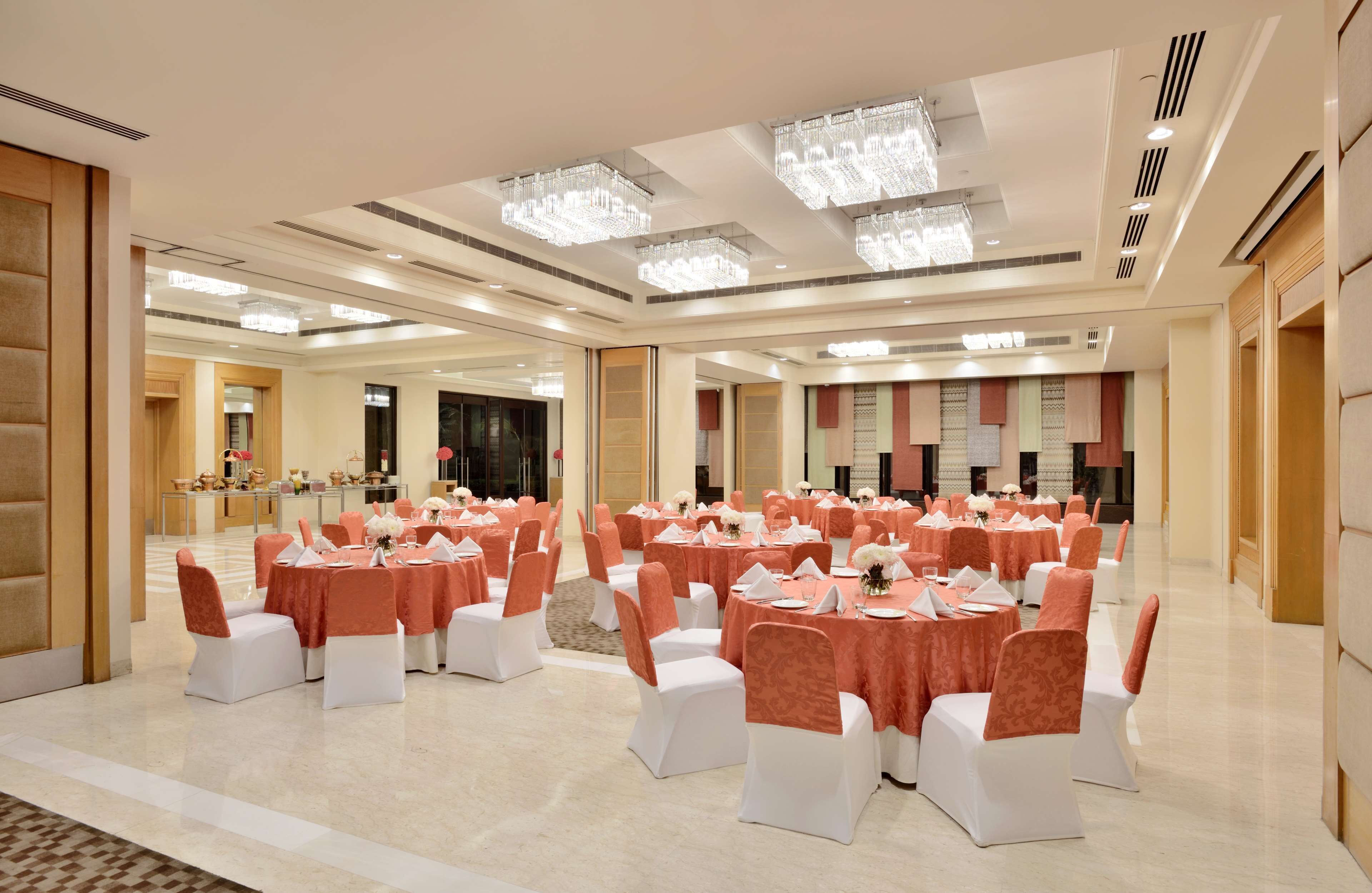 A spacious banquet hall with round tables, white chairs, and peach-colored tablecloths.