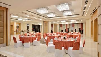 A spacious banquet hall with round tables, white chairs, and peach-colored tablecloths.