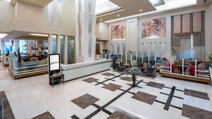 A spacious lobby with a high ceiling, a reception desk, and a seating area with modern furniture. - Radisson Noida (Noida)