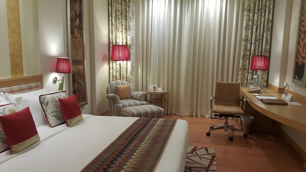 Una habitación de hotel con una cama grande, un escritorio, una silla y una mesita.