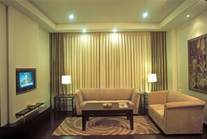 A living room with a sofa, a coffee table, and a TV mounted on the wall.