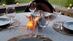 A table set for a meal with wine glasses, plates, and cutlery, overlooking a swimming pool and garden. - Casa de Santa Ana da Beira (Seia)