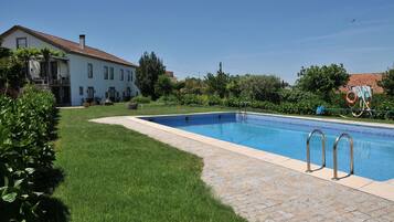 Una piscina al aire libre, sombrillas, sillones reclinables de piscina