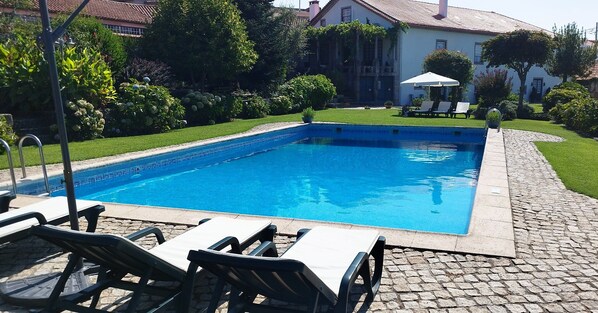 Una piscina al aire libre, sombrillas, tumbonas
