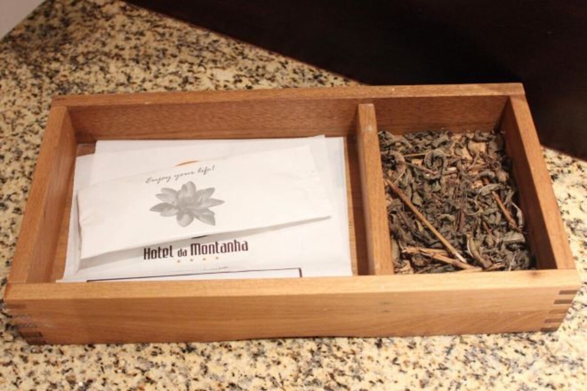 Una caja de madera con un sobre blanco y hierbas secas.