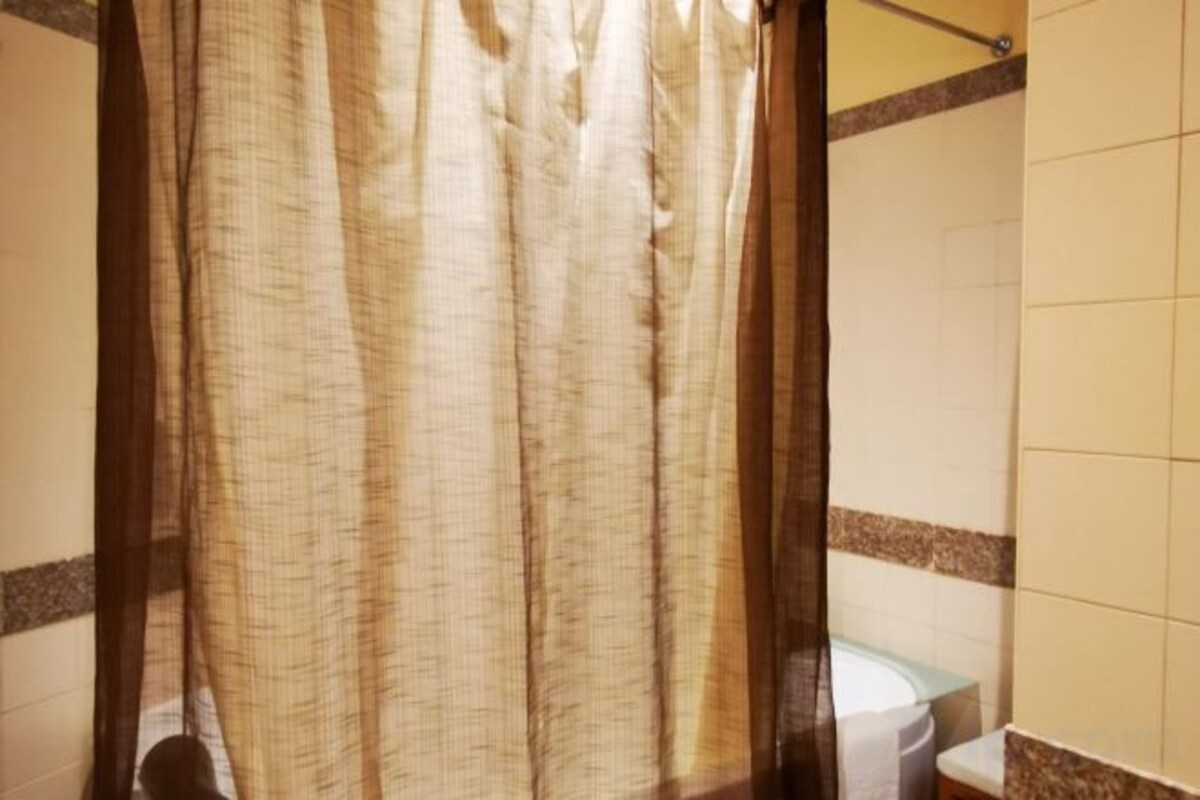Un baño con cortina de ducha, inodoro y paredes con azulejos.