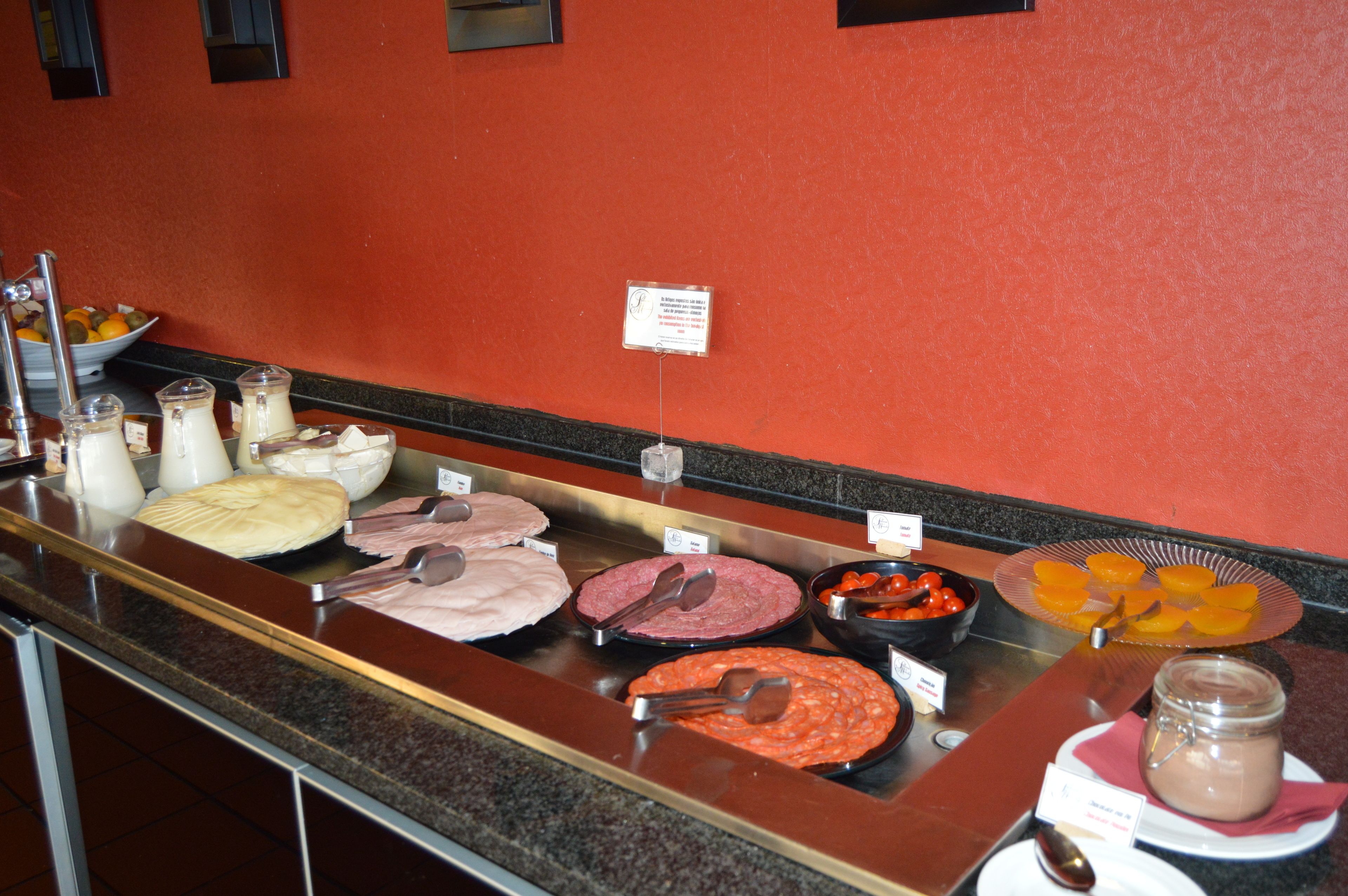A buffet counter with various food items and a sign on the wall.
