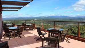 Una terraza con mobiliario exterior y una vista panorámica de montañas y vegetación.