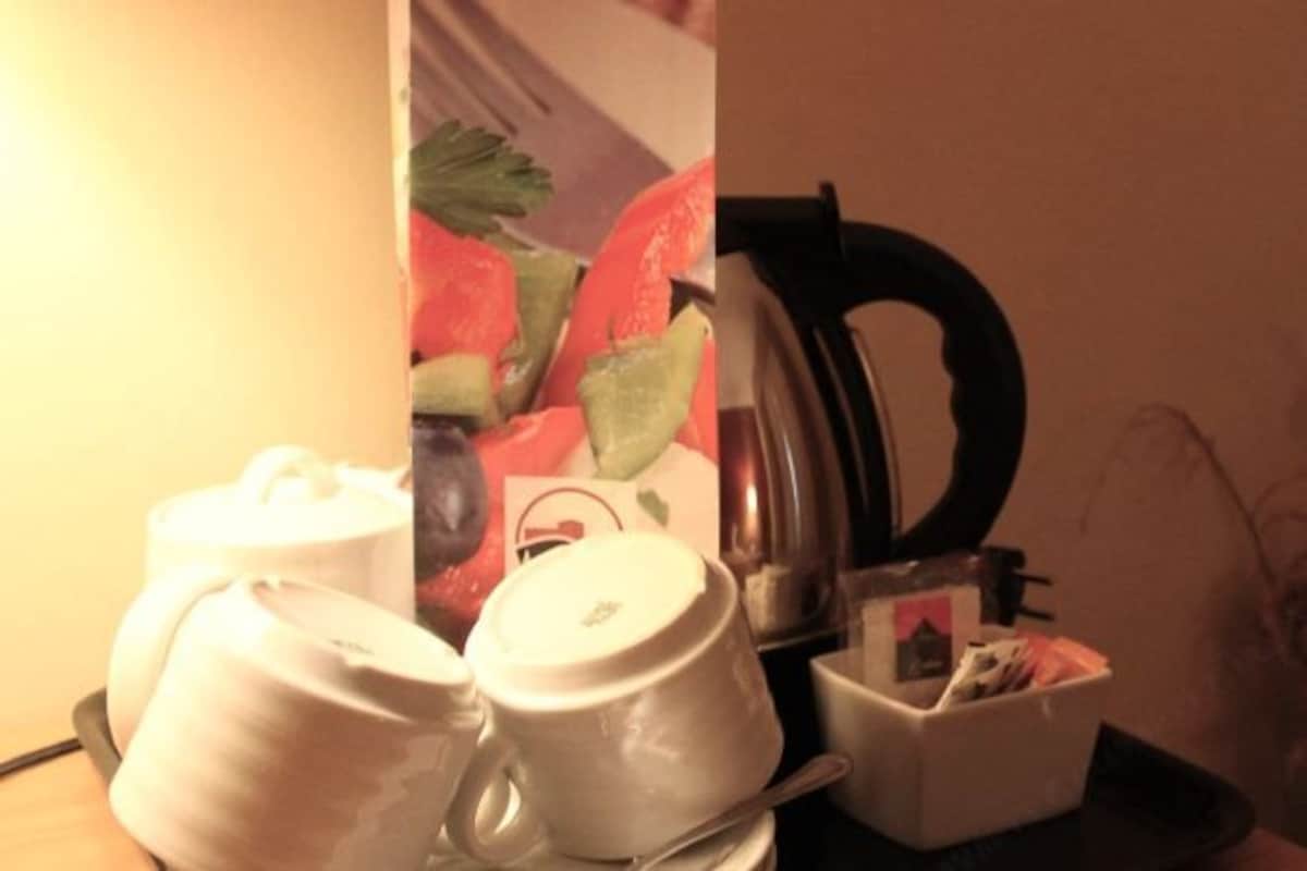 Un área de cocina con hervidor, cafetera y un juego de tazas blancas sobre una bandeja.