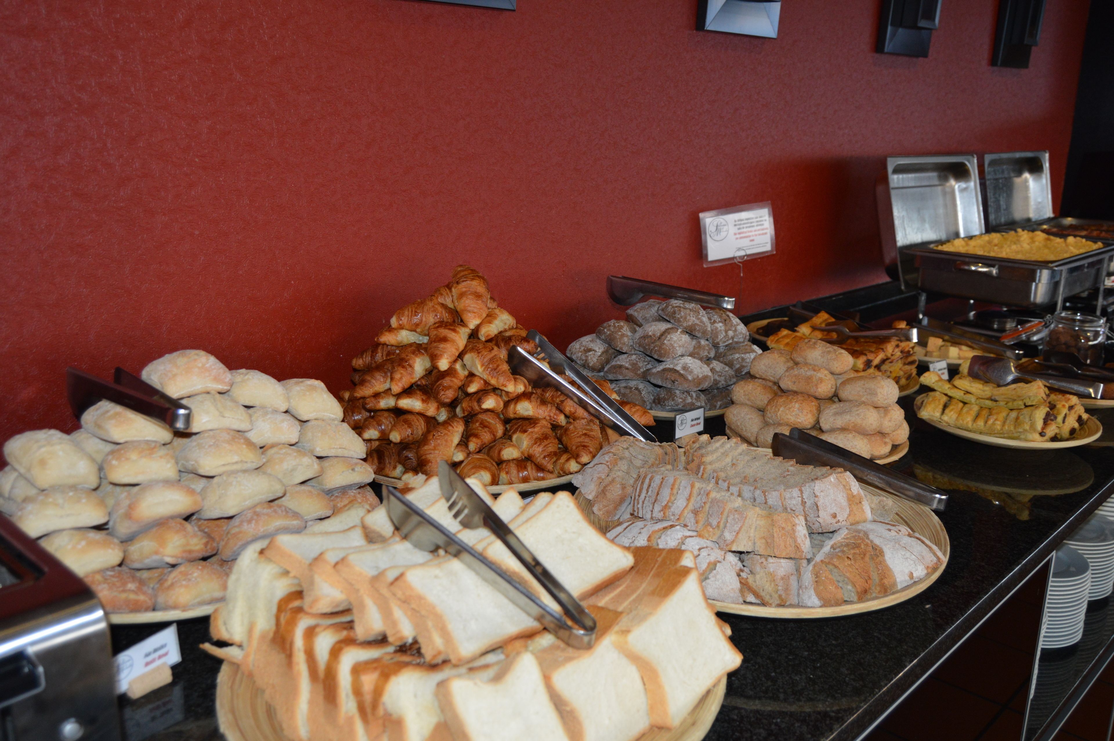 A buffet with various food items including bread, pastries, and other baked goods.
