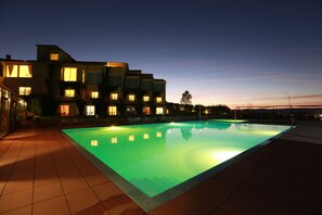 Un edificio moderno con piscina al anochecer.
