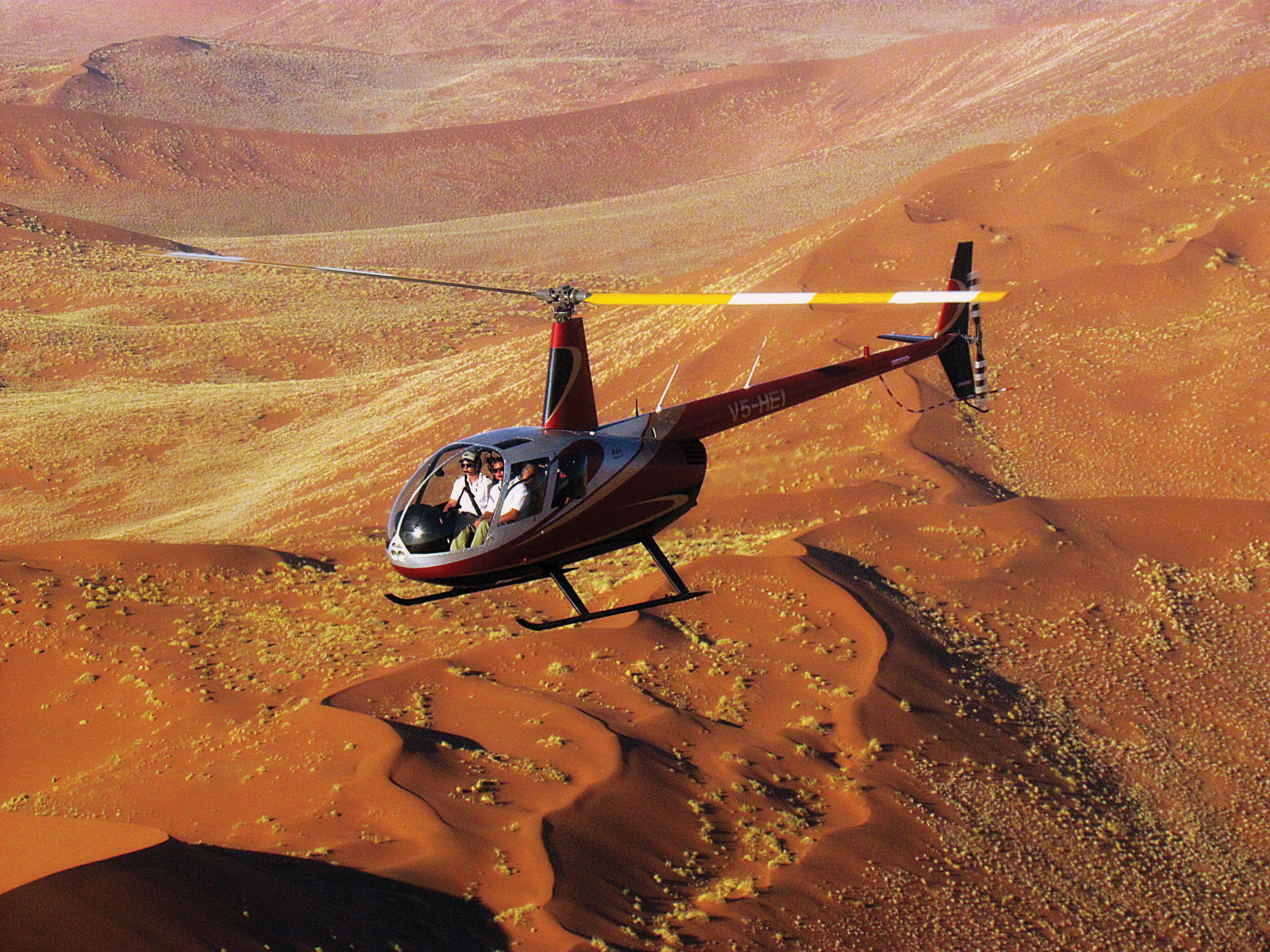 En helikopter flyver over et ørkenlandskab.