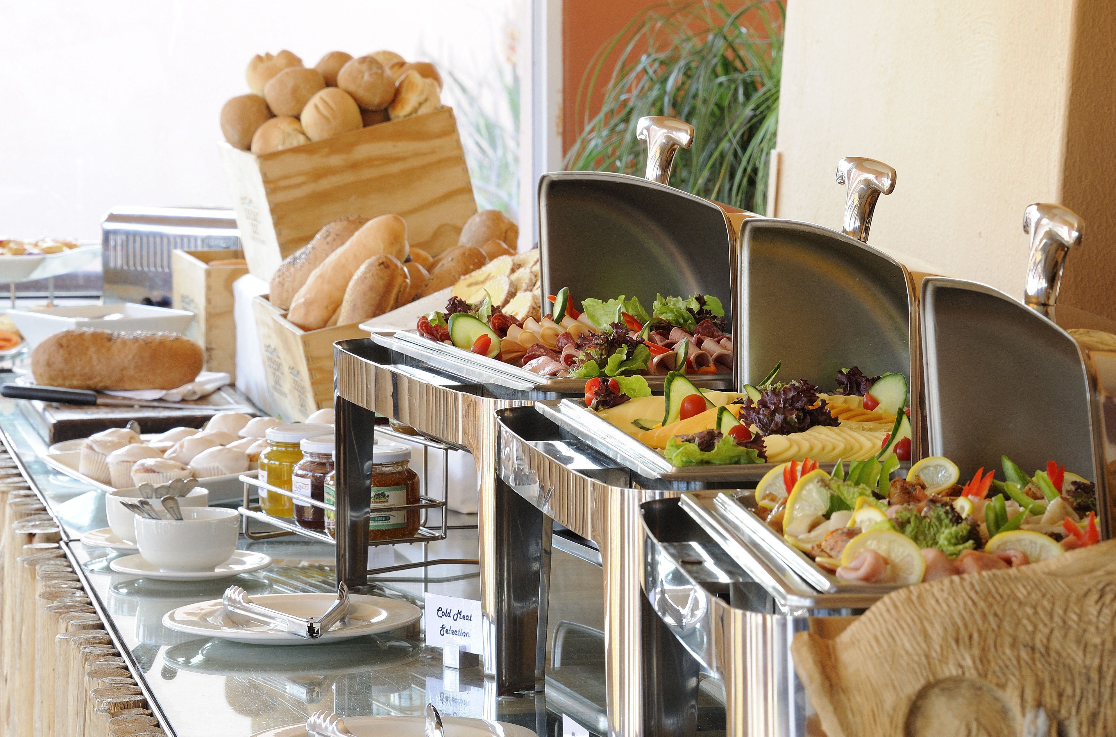 A buffet with various food items including bread, salads, and cold cuts.