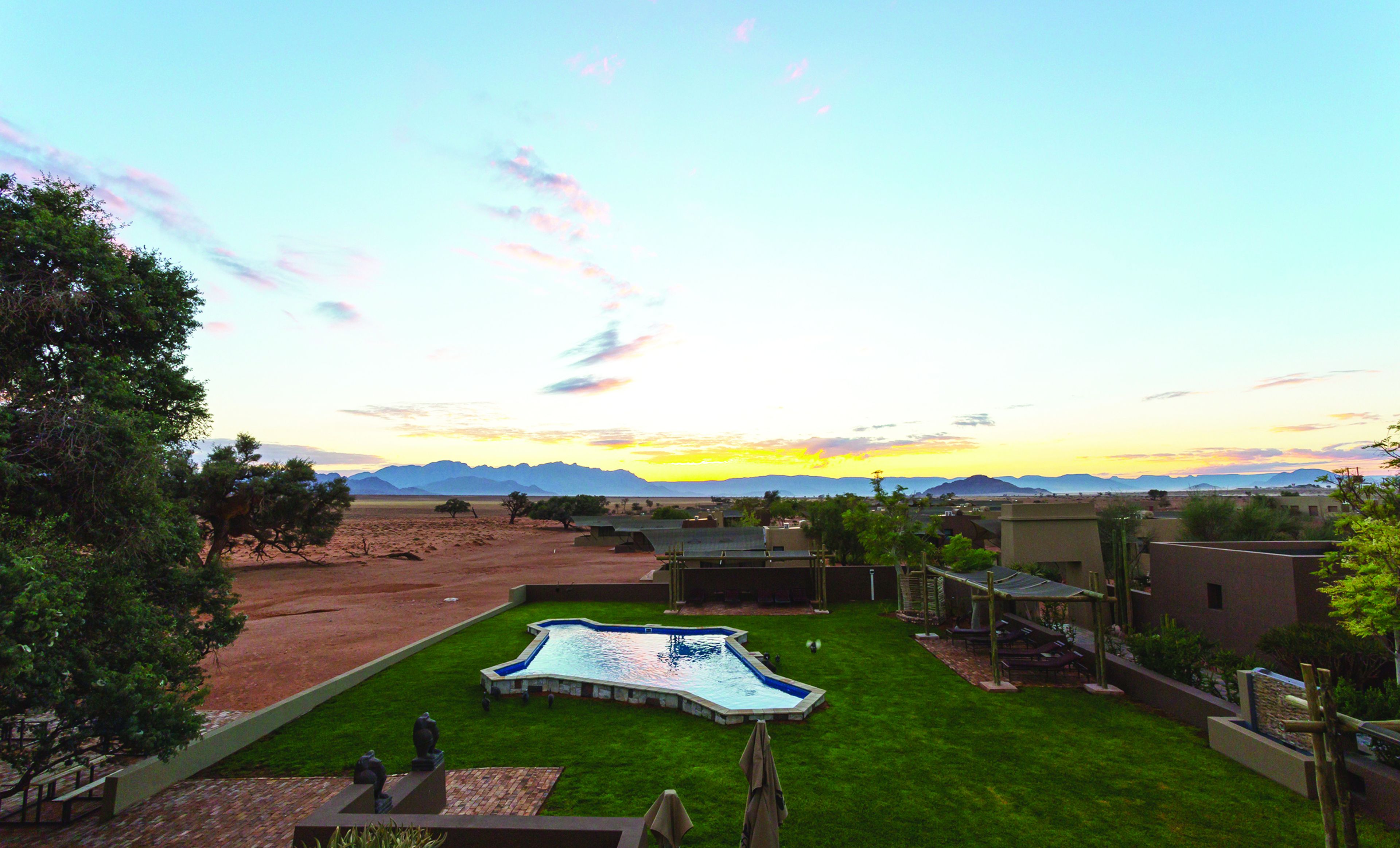 Zona residencial con piscina, césped verde y casas de techo plano.