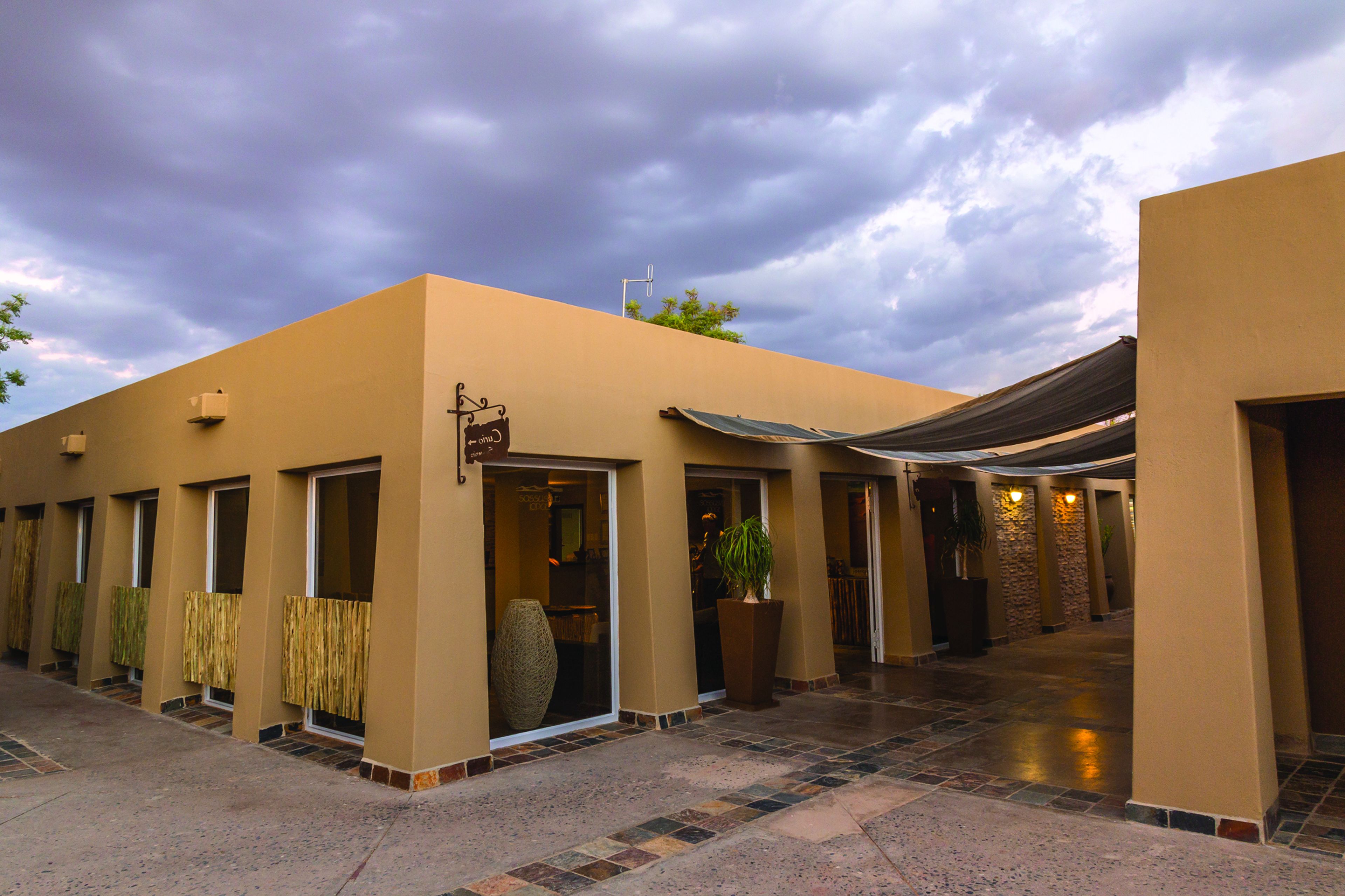 A hotel entrance with a covered walkway, a reception area, and a large potted plant.