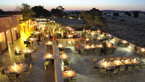 An outdoor dining area with tables and chairs arranged for guests. - Sossusvlei Lodge (Sesriem)