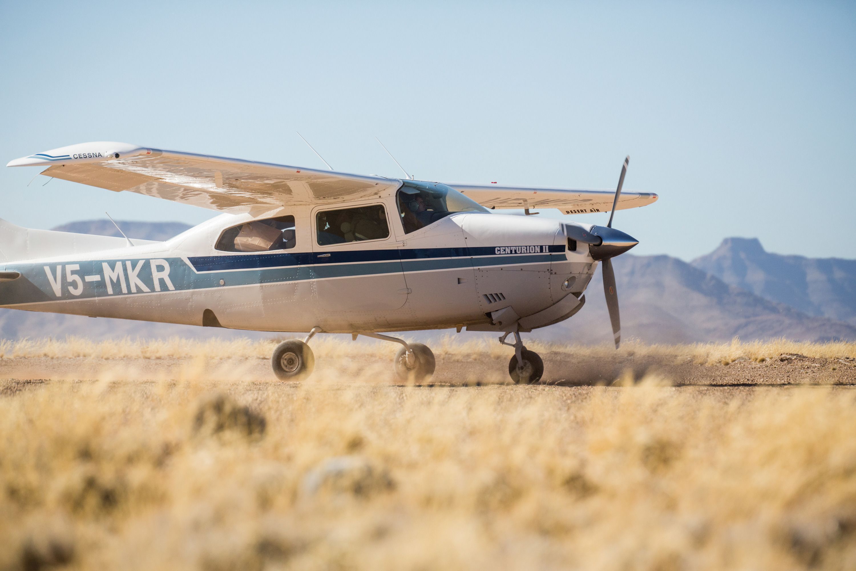 Un petit avion à hélice, immatriculé V5-MKR, se trouve sur un champ d’herbe.