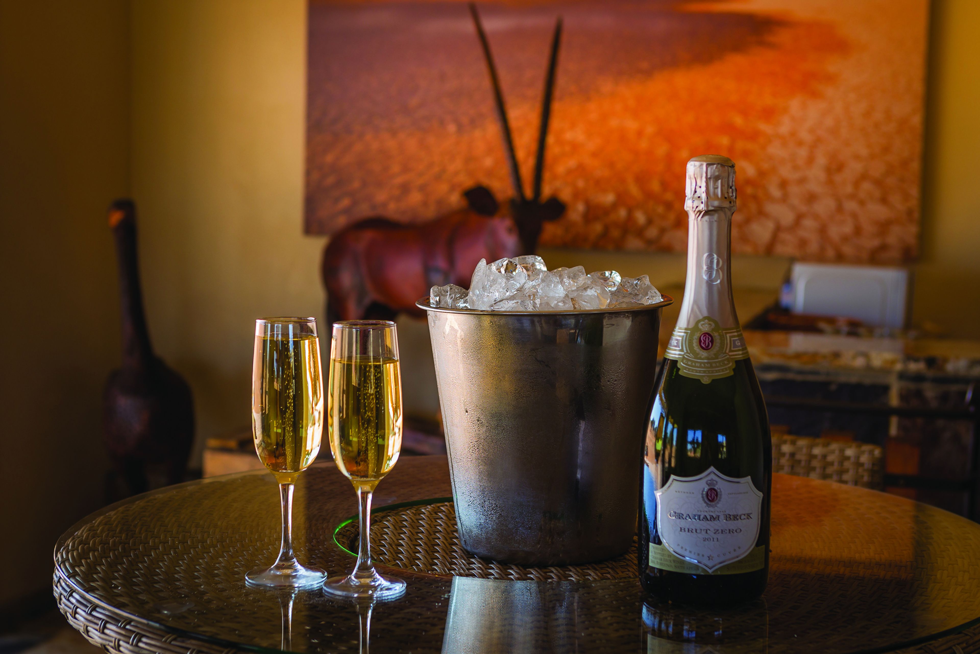 Une table avec une bouteille de champagne, deux verres et un seau en métal rempli de glace.