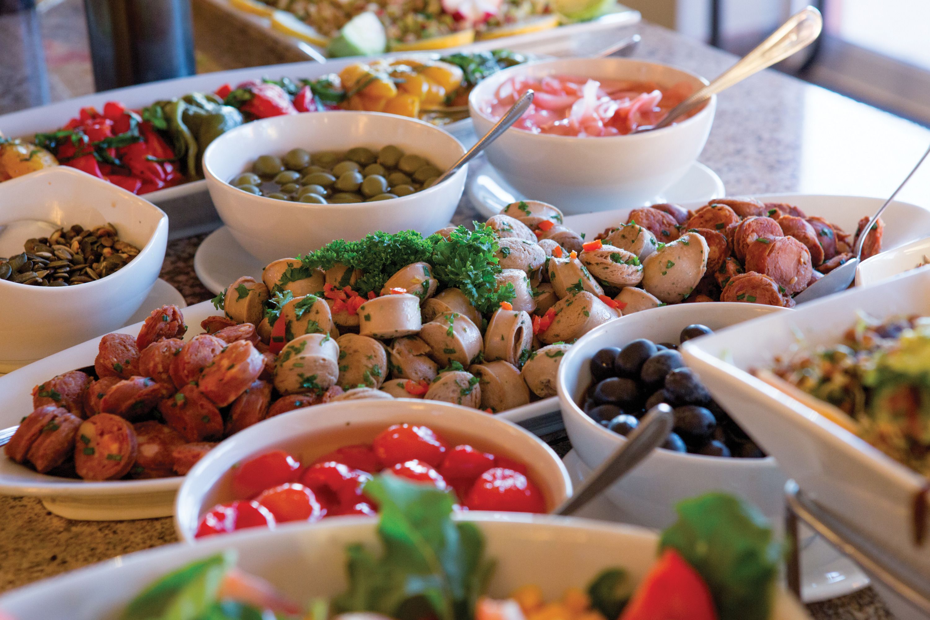 Ein Buffet mit verschiedenen Speisen, darunter Oliven, Tomaten und Würstchen.