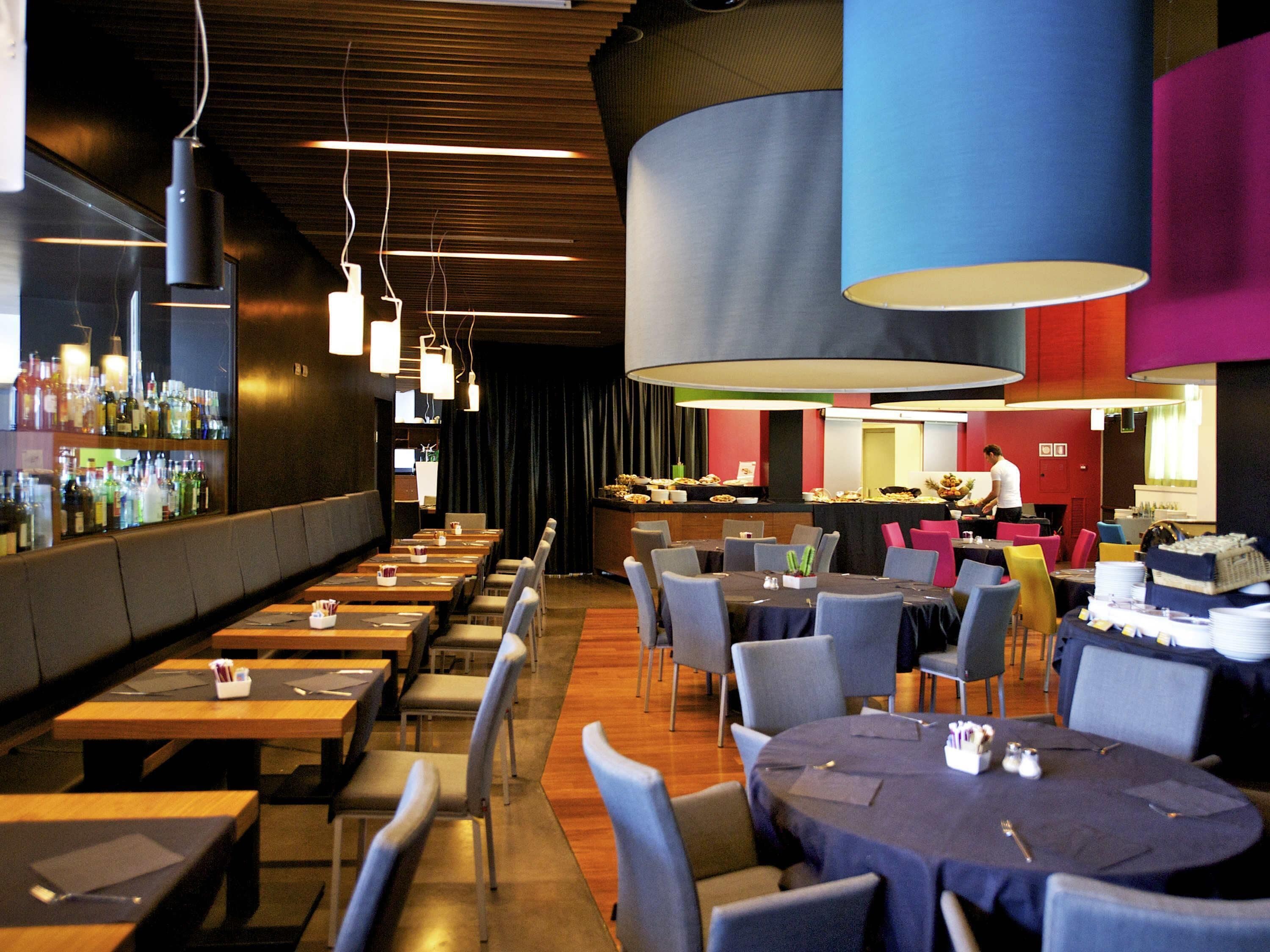 Un restaurant doté de plusieurs tables, de chaises et d’un bar où sont exposées des bouteilles.