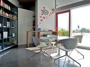 A modern office with a glass table, white chairs, a bookshelf, and a wall clock. - Mercure Nerocubo Rovereto (Rovereto)